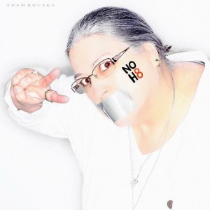 NoH8 photo, silver-grey haired woman flashing peace sign