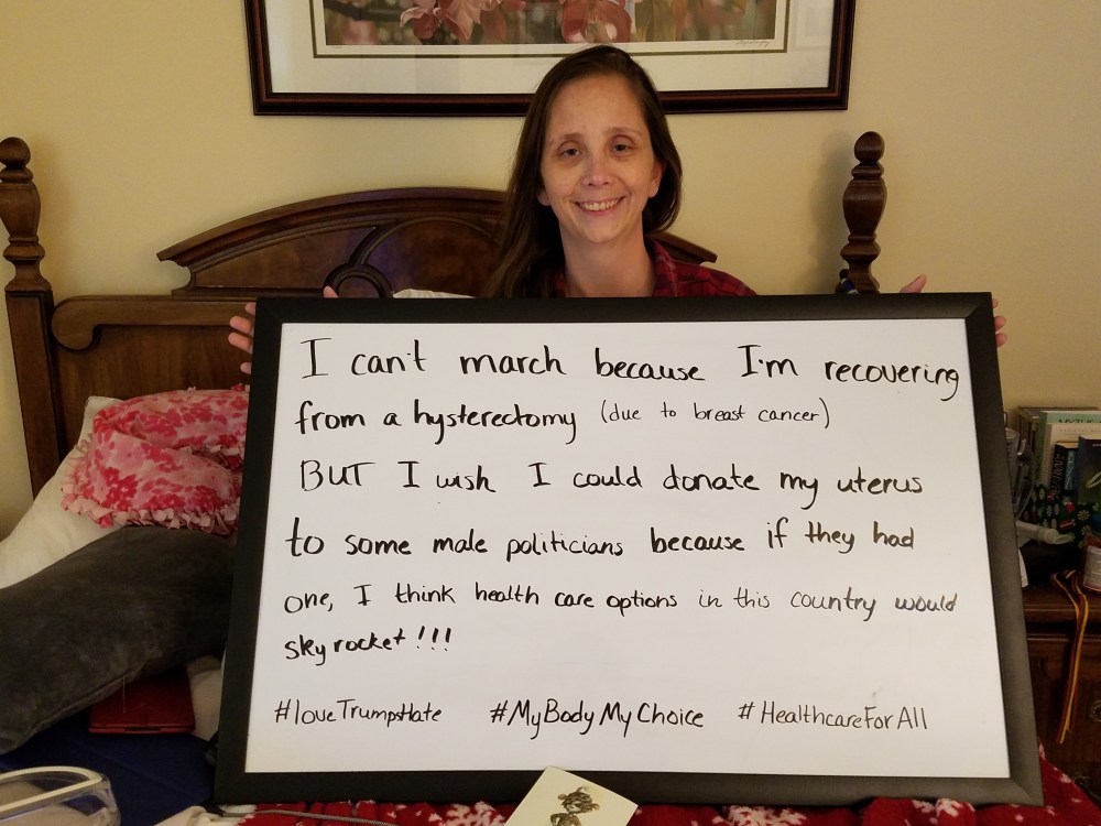 Woman sitting on a bed with a large dry-erase board. Her statement (below) is written on the dry erase board.