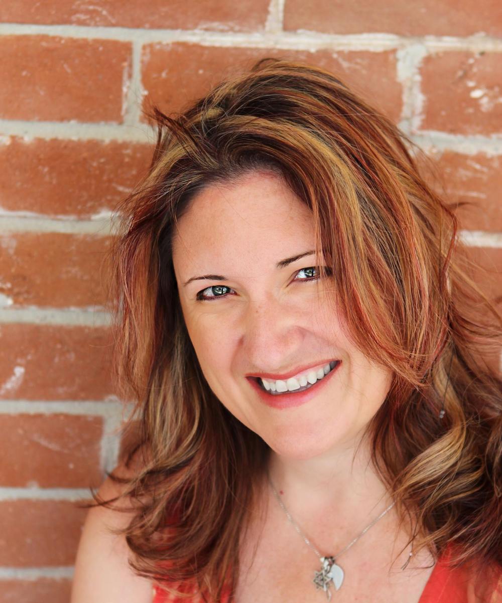 a-woman-in-orange-standing-against-a-brick-wall