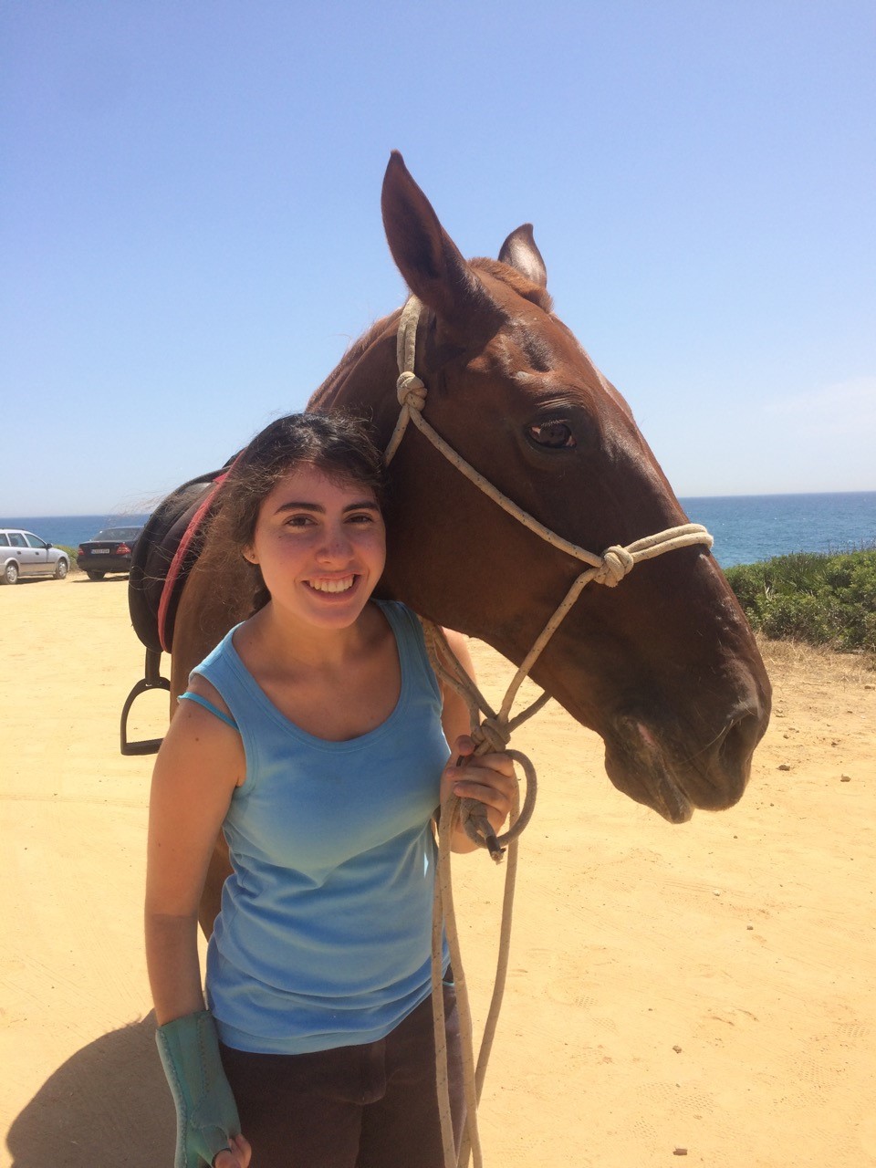 dark-haired-girl-standing-next-to-a-horse-and-holding-it-by-the-reins