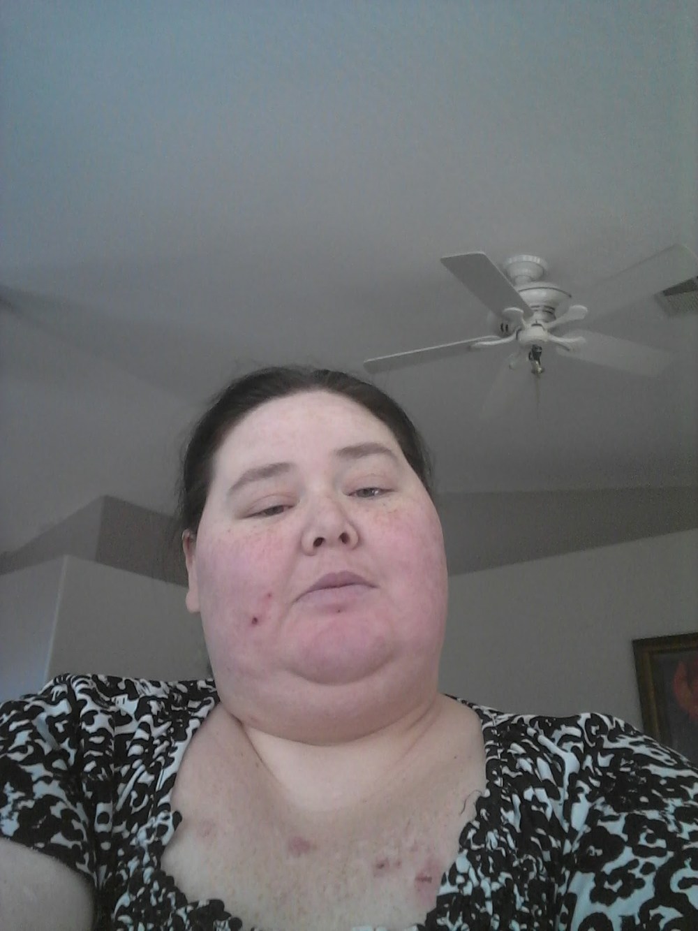 A woman that is 29 yr old looking into the camera. Long hair in a messy bun.