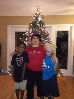 Marlene-mom with osteogenesis imperfecta Son William with sensory processing disorder Daughter Neylan with albinism low vision and glycogen storage disorder XI and developmental delays All stand in front of a decorated Christmas tree.