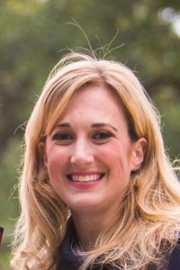 Headshot of Ryann outside on a sunny day, facing the camera and smiling.