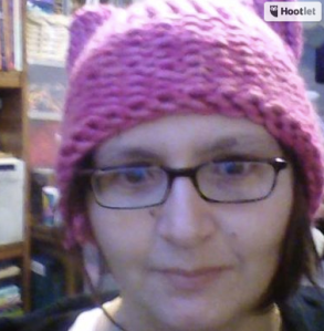 A woman with glasses and a knit pink hat with ears on her head.