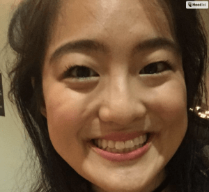 A closeup of a young Asian woman smiling into the camera.